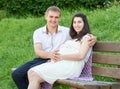 Happy couple in summer city park outdoor, pregnant woman, bright sunny day and green grass, beautiful people portrait Royalty Free Stock Photo