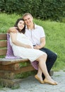 Happy couple in summer city park outdoor, pregnant woman, bright sunny day and green grass, beautiful people portrait, yellow tone Royalty Free Stock Photo