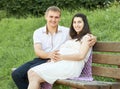 Happy couple in summer city park outdoor, pregnant woman, bright sunny day and green grass, beautiful people portrait, yellow tone Royalty Free Stock Photo