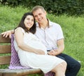 Happy couple in summer city park outdoor, pregnant woman, bright sunny day and green grass, beautiful people portrait, yellow tone Royalty Free Stock Photo