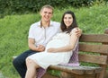 Happy couple in summer city park outdoor, pregnant woman, bright sunny day and green grass, beautiful people portrait, yellow tone Royalty Free Stock Photo