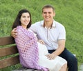 Happy couple in summer city park outdoor, pregnant woman, bright sunny day and green grass, beautiful people portrait, yellow tone Royalty Free Stock Photo