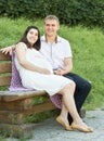 Happy couple in summer city park outdoor, pregnant woman, bright sunny day and green grass, beautiful people portrait, yellow tone Royalty Free Stock Photo