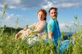 Happy couple in summer grass on sky background. Together man and woman sitting in field Royalty Free Stock Photo