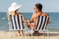 Happy couple sunbathing in chairs on summer beach Royalty Free Stock Photo