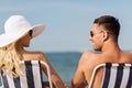 Happy couple sunbathing in chairs on summer beach Royalty Free Stock Photo