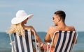 Happy couple sunbathing in chairs on summer beach Royalty Free Stock Photo