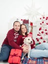 Happy couple with dog, all in Christmas clothes sitting near Christmas tree Royalty Free Stock Photo