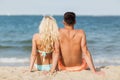 Happy couple in swimwear sitting on summer beach Royalty Free Stock Photo