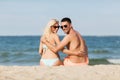 Happy couple in swimwear sitting on summer beach Royalty Free Stock Photo