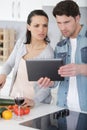 happy couple with tablet and credit card in kitchen