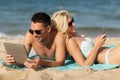 Happy couple with tablet pc sunbathing on beach Royalty Free Stock Photo