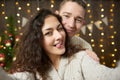 Happy couple taking selfie and having fun in christmas decoration. Dark wooden interior with lights. Romantic evening and love con