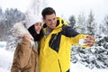Happy couple taking selfie near snowy forest. Winter vacation Royalty Free Stock Photo