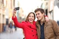 Happy couple taking selfies in the street in winter