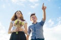 Happy couple of teens boy and girl 14, 15 years old. Young people smiling and talking, blue sky background