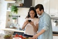Happy couple tenants cooking at home using cellphone Royalty Free Stock Photo