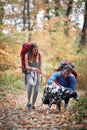 Happy couple and their dog at hiking through fallen leaves Royalty Free Stock Photo