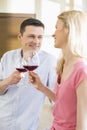 Happy couple toasting red wine glasses in kitchen Royalty Free Stock Photo