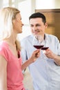 Happy couple toasting red wine glasses in kitchen Royalty Free Stock Photo