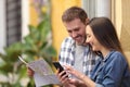 Happy couple of tourists checking phone and map