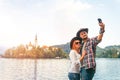 Happy couple of tourists in love take a selfie on a smartphone on the background with Bled Lake and Church on the Island, Slovenia Royalty Free Stock Photo