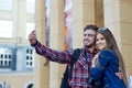 Happy couple of tourists taking selfie in showplace of city