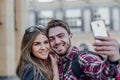 Happy couple of tourists taking selfie in showplace of city. Man and woman making photo on city background Royalty Free Stock Photo