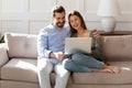Happy couple using laptop together, relaxing on cozy couch Royalty Free Stock Photo