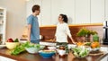 Happy couple, vegetarians talking while going to prepare healthy meal, sandwhich, salad in the kitchen together Royalty Free Stock Photo