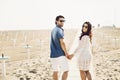 Happy couple walking along the sea, holding hands. Girl in white dress, man in a jeans shirt. Love story. Back view Royalty Free Stock Photo