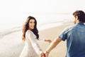 Happy couple walking along the sea, holding hands. Girl in white dress, man in a jeans shirt. Love story. Back view Royalty Free Stock Photo