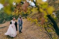 A happy couple is walking on a trail in an autumn forest. Bride and groom with dreadlocks are looking at each other on Royalty Free Stock Photo