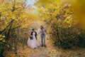 A happy couple is walking on a trail in an autumn forest. Bride and groom with dreadlocks are looking at each other on Royalty Free Stock Photo