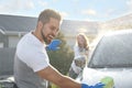 Happy couple washing car and having fun at backyard on sunny day Royalty Free Stock Photo