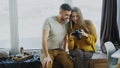 Happy smiling couple watching photos from travel on digital camera at home after vacation Royalty Free Stock Photo