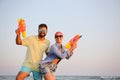 Happy couple with water guns near sea