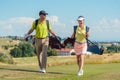 Happy couple wearing golf outfits and carrying stand bags Royalty Free Stock Photo