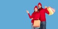 Happy Couple Wearing Winter Hats Holding Shopping Bags Pointing At Copy Space Royalty Free Stock Photo