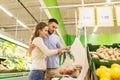 Happy couple weighing tomatoes on scale at grocery Royalty Free Stock Photo