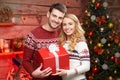 Happy Couple in winter pullovers smiling and holding big red gift box