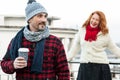 Happy couples loves coffee. Smiling guy holds craft cup with coffee hiding from girlfriend behind. Man with coffee and girlfriend Royalty Free Stock Photo