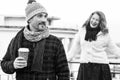 Happy couples loves drink coffee outdoor. Smiling guy holds craft cup with coffee and hiding it from girlfriend behind. Royalty Free Stock Photo