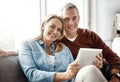 Happy couples stay connected. a mature couple using a digital tablet while relaxing together on the sofa at home. Royalty Free Stock Photo