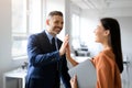 Happy coworkers celebrating achievement in office, man and woman giving high five and smiling, enjoying job well done Royalty Free Stock Photo