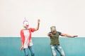 Happy crazy couple dancing while wearing t-rex and unicorn mask outdoor - Seniors having fun celebrating carnival fest Royalty Free Stock Photo