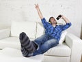 Happy crazy man on couch listening to music holding mobile phone as microphone Royalty Free Stock Photo