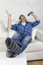 Happy crazy man on couch listening to music holding mobile phone as microphone Royalty Free Stock Photo