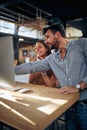 Blurred faces of young man and woman colleagues talking in front of table with desktop computer, in clothing store Royalty Free Stock Photo