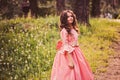 Happy curly child girl in fairytale princess pink dress dancing in summer forest Royalty Free Stock Photo